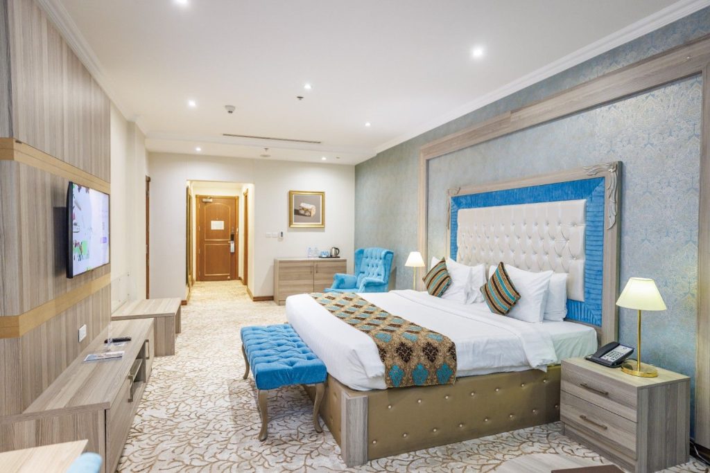 Spacious Deluxe King Room at Sapphire Plaza Hotel Doha with Blue Armchair and Modern Interior